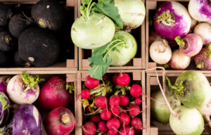 commodity market report for insidetrack - Some of fresh red, black, white and different radishes in a wooden farmer case top view.