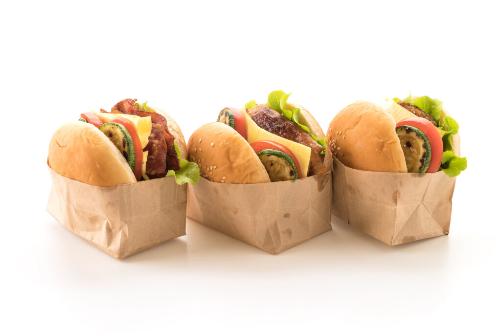 Close-up of three hamburgers highlighting the toasted, golden buns stacked on a wooden board.