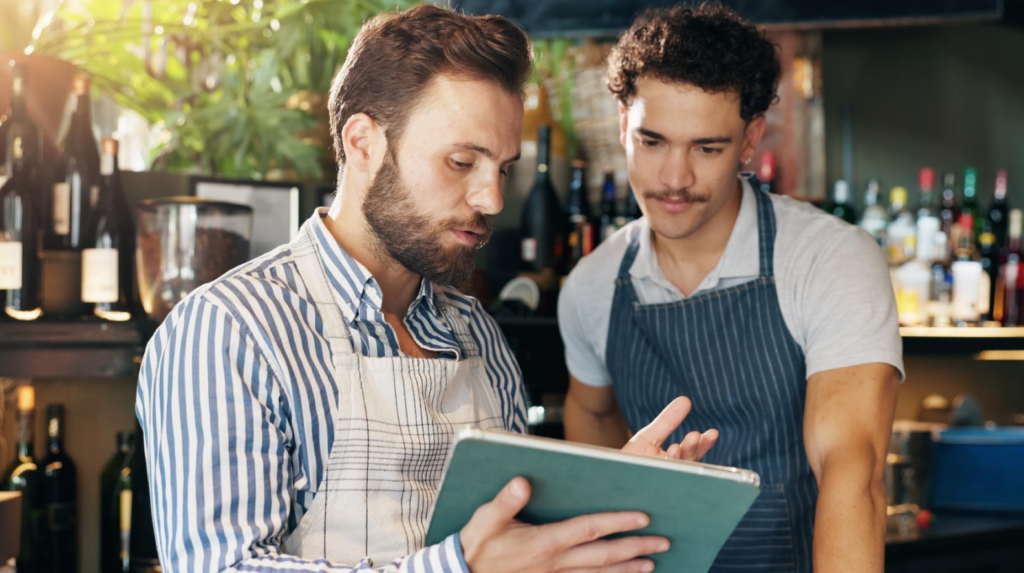 Restaurant managers reviewing data on a tablet as part of a restaurant cost analysis