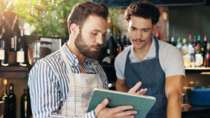 Restaurant managers reviewing data on a tablet as part of a restaurant cost analysis