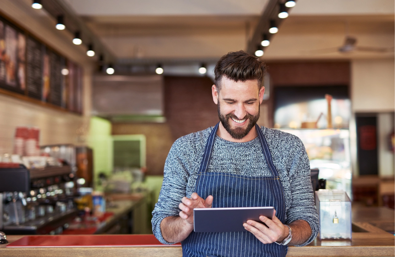 Restaurant operator using a tablet at a cafe counter to review foodservice procurement KPIs